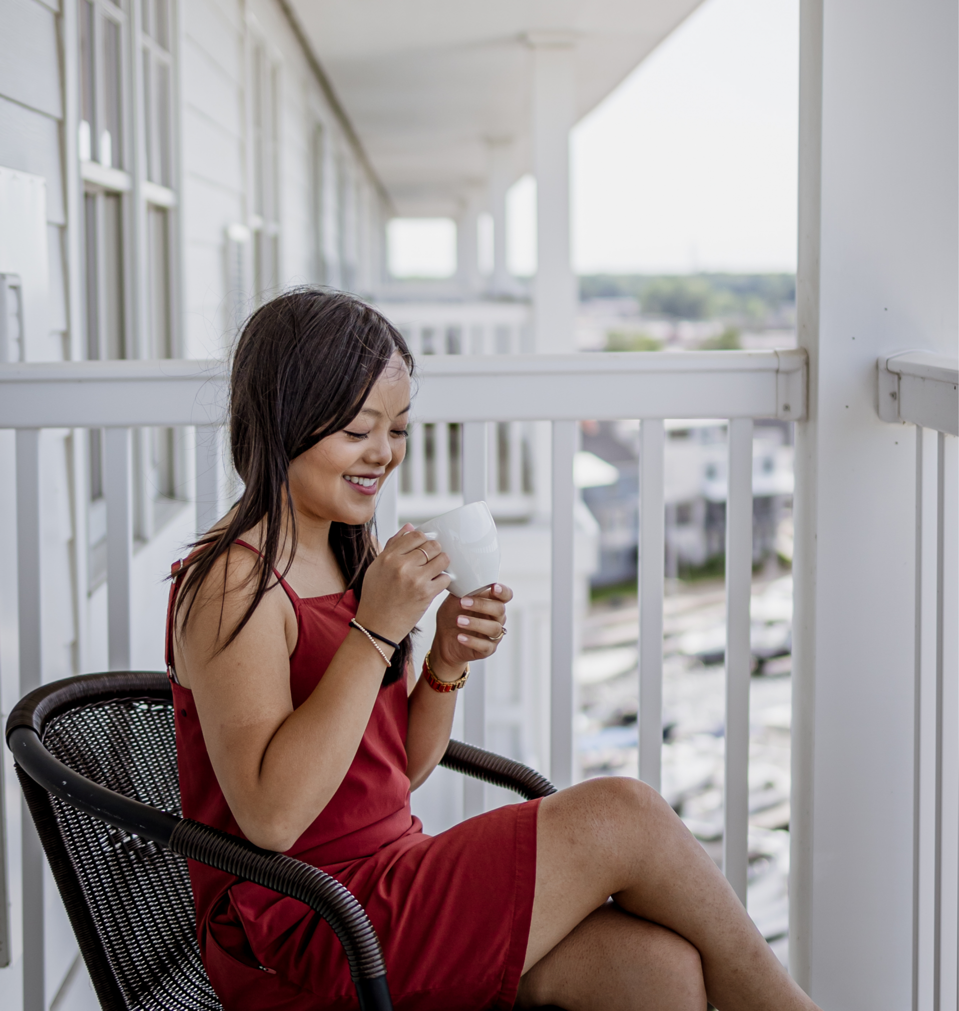 Rachel Kawate sipping coffee on her hotel room balcony at the Inn at Harbor Shores