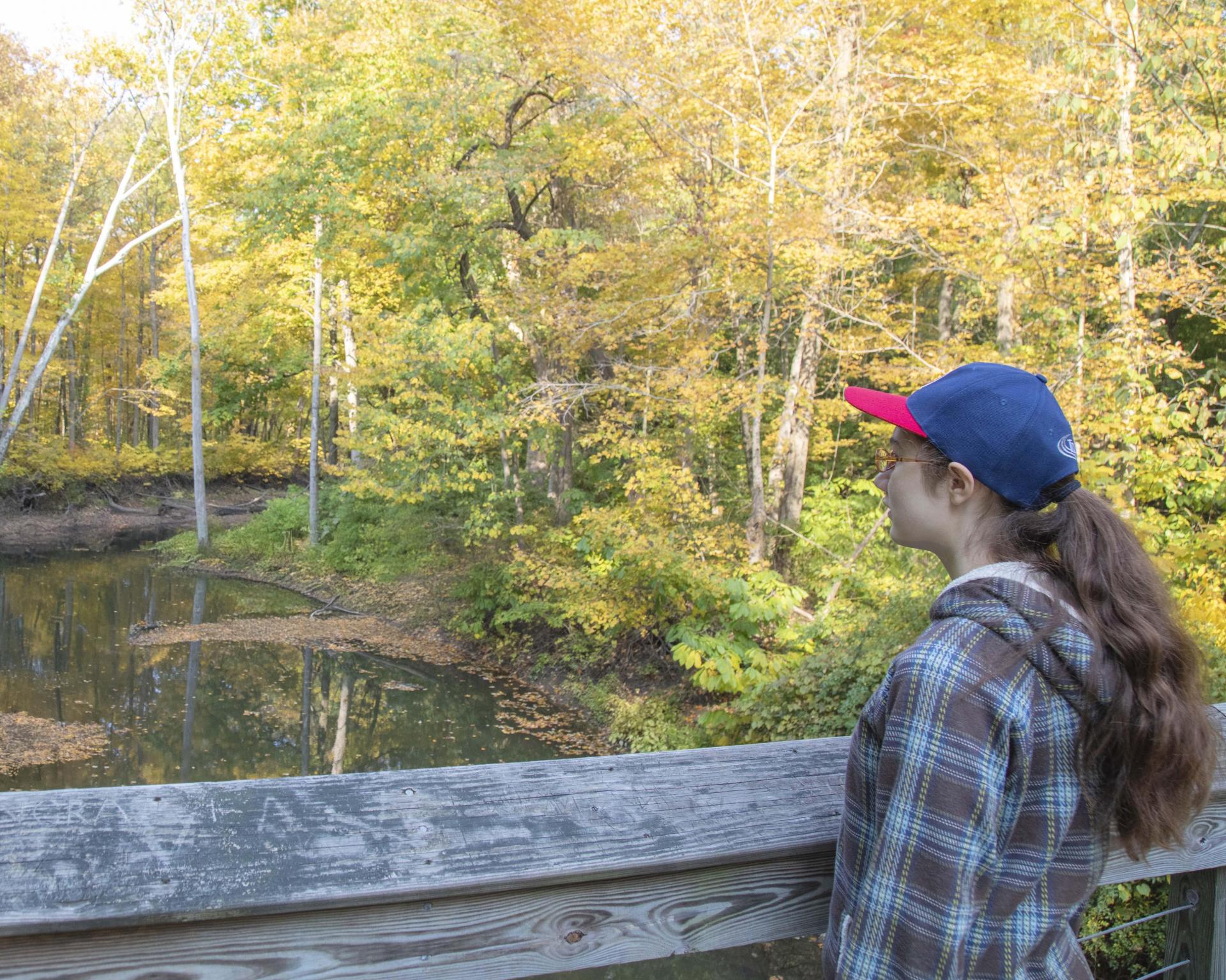 A young lady enjoying the view of fall color on a bridge at Warren Woods State Park.