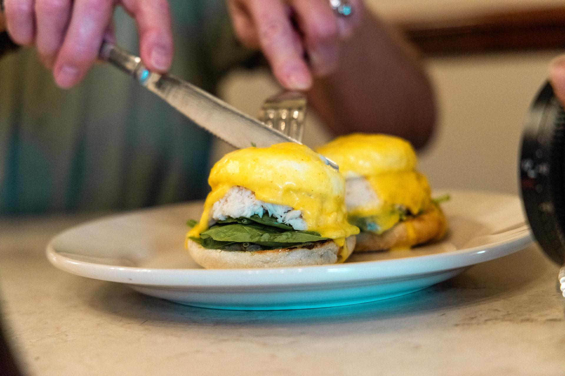 A person cutting into an Eggs Benedict at the Copper Pot.