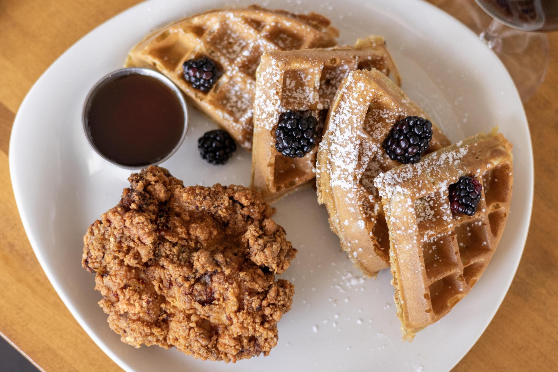 Chicken and waffles with blackberries and syrup on the side at Planks