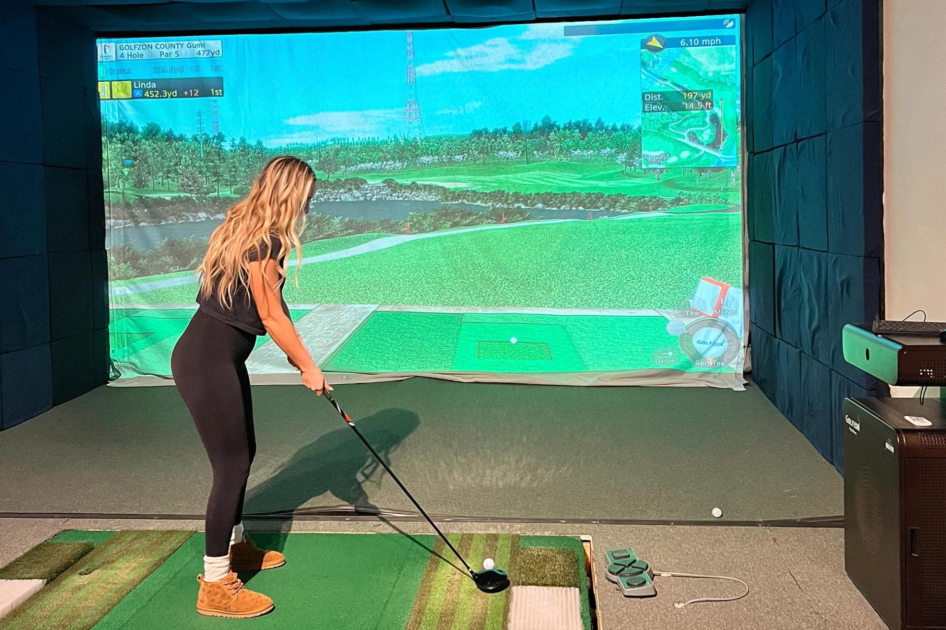 A player tees off in an indoor golf simulator.