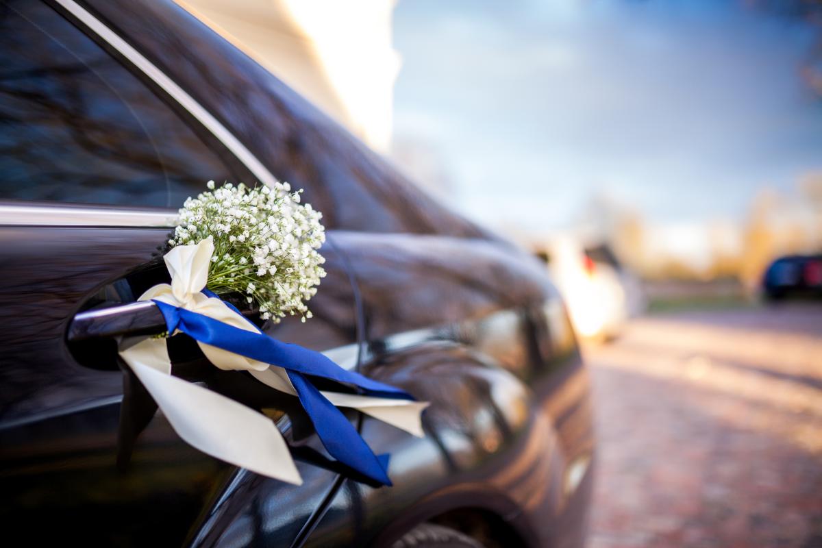 A car decorated with flowers and ribbons tied to the door handle.