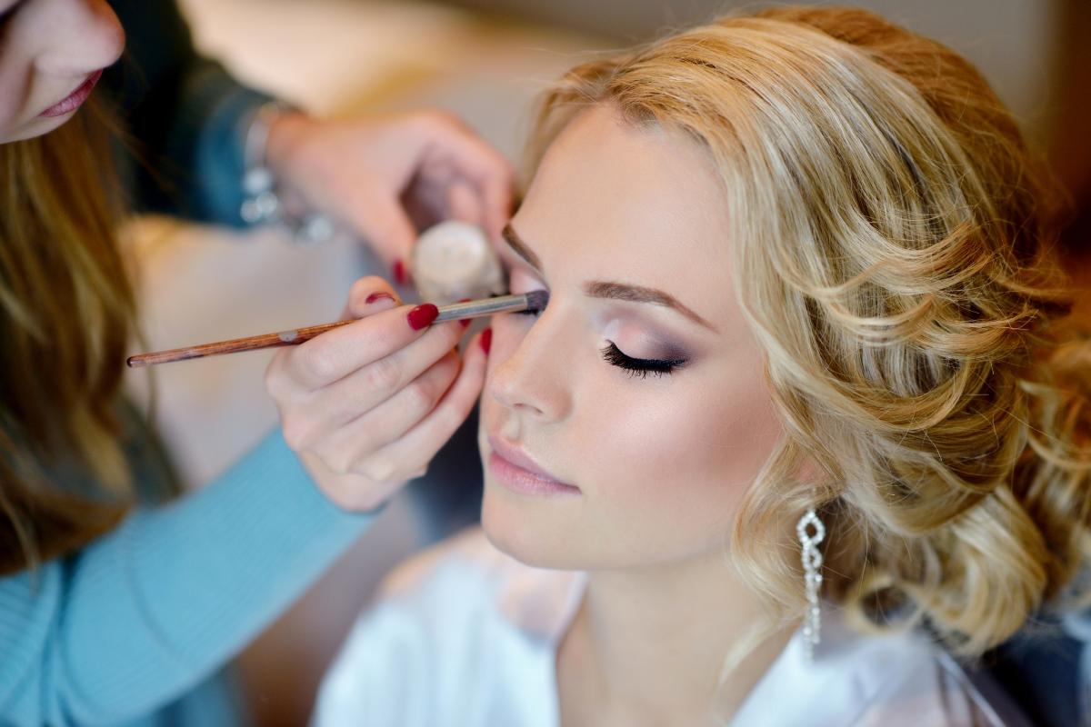 A bride getting her makeup done by a professional makeup artist.