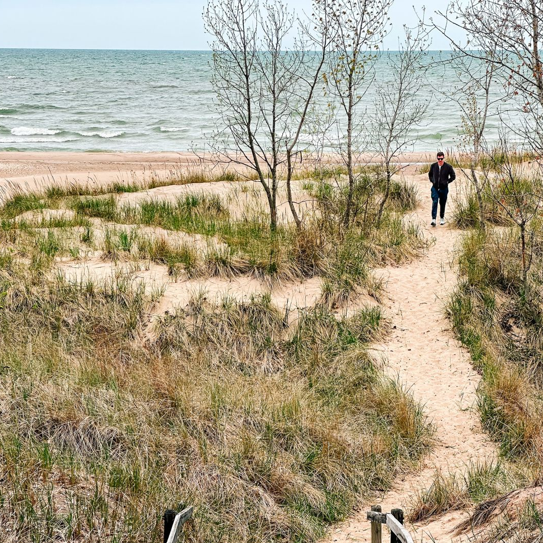 A person walks along a trail leading to the beach at Warren Dunes State Park.