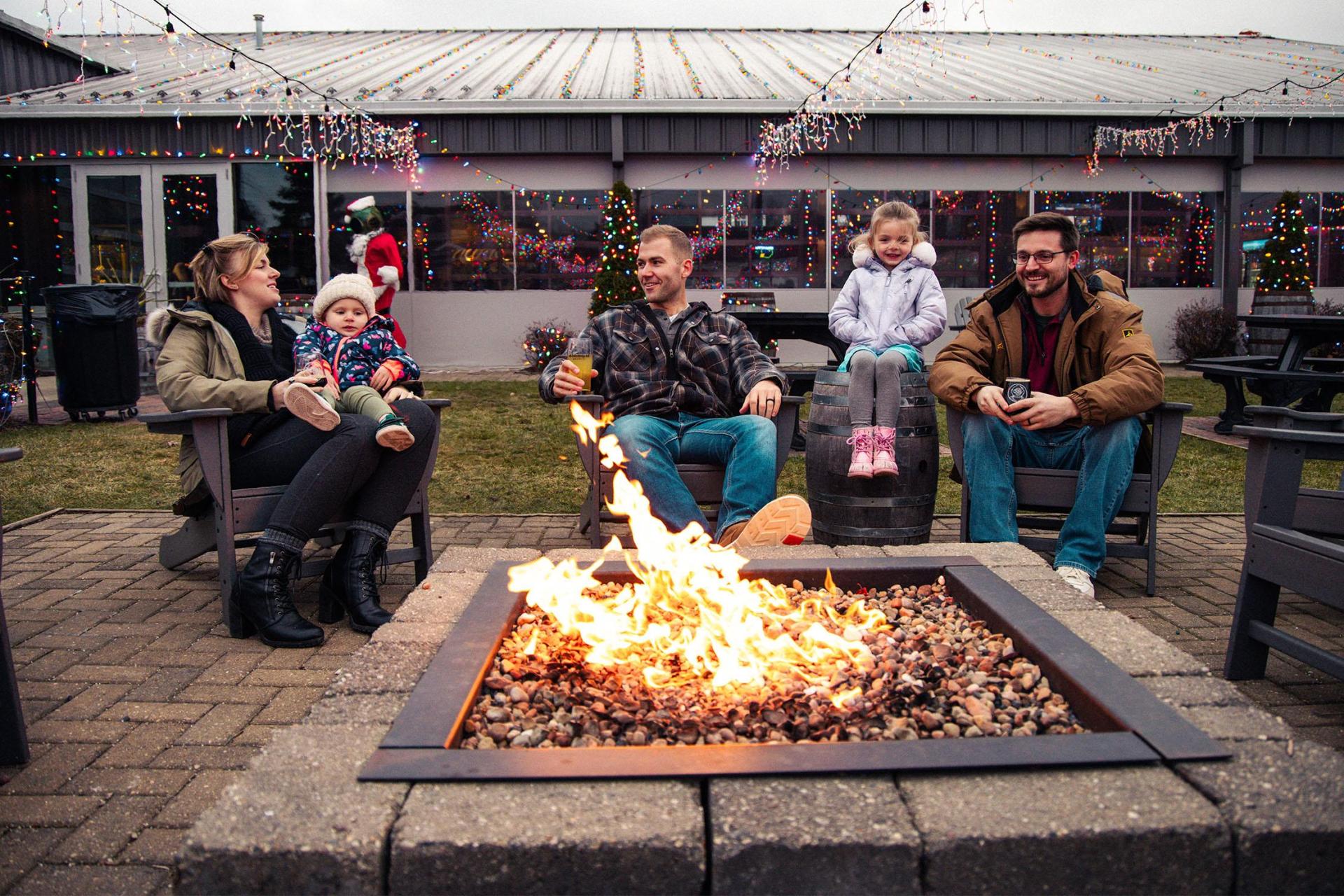 A group of friends enjoy drinks and warmth by the fire at Watermark Brewery.
