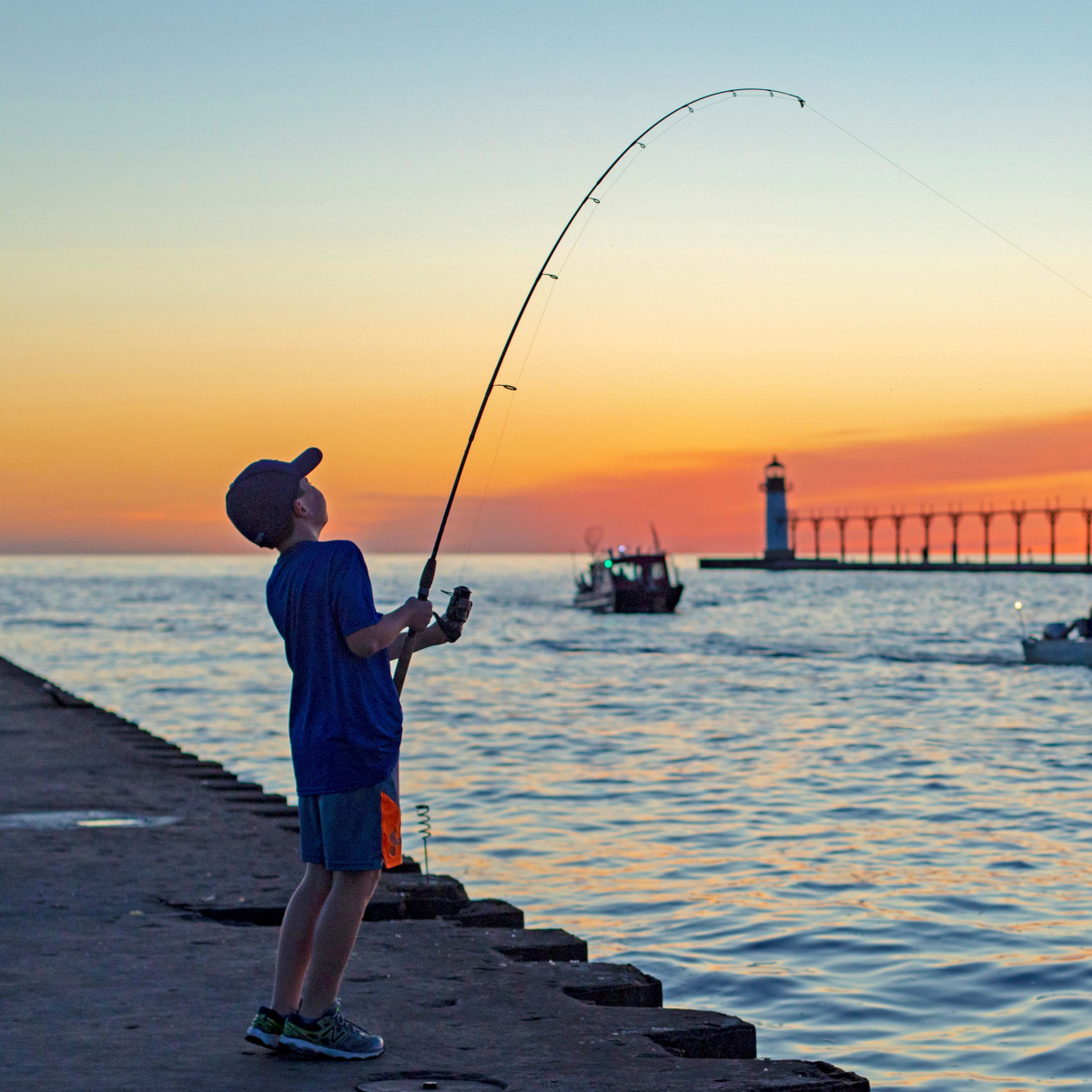 A-boy-fishing-near-the-lighthouse-at-sunset