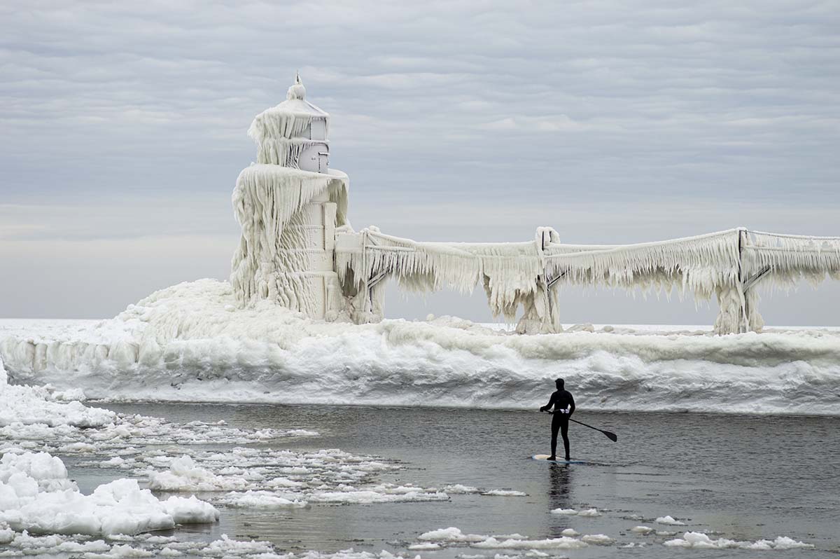 Winter Vacation at St. Joe Lighthouse A paddleboard surfer braves the cold water and gets up close to the frozen lighthouse during their winter vacation
